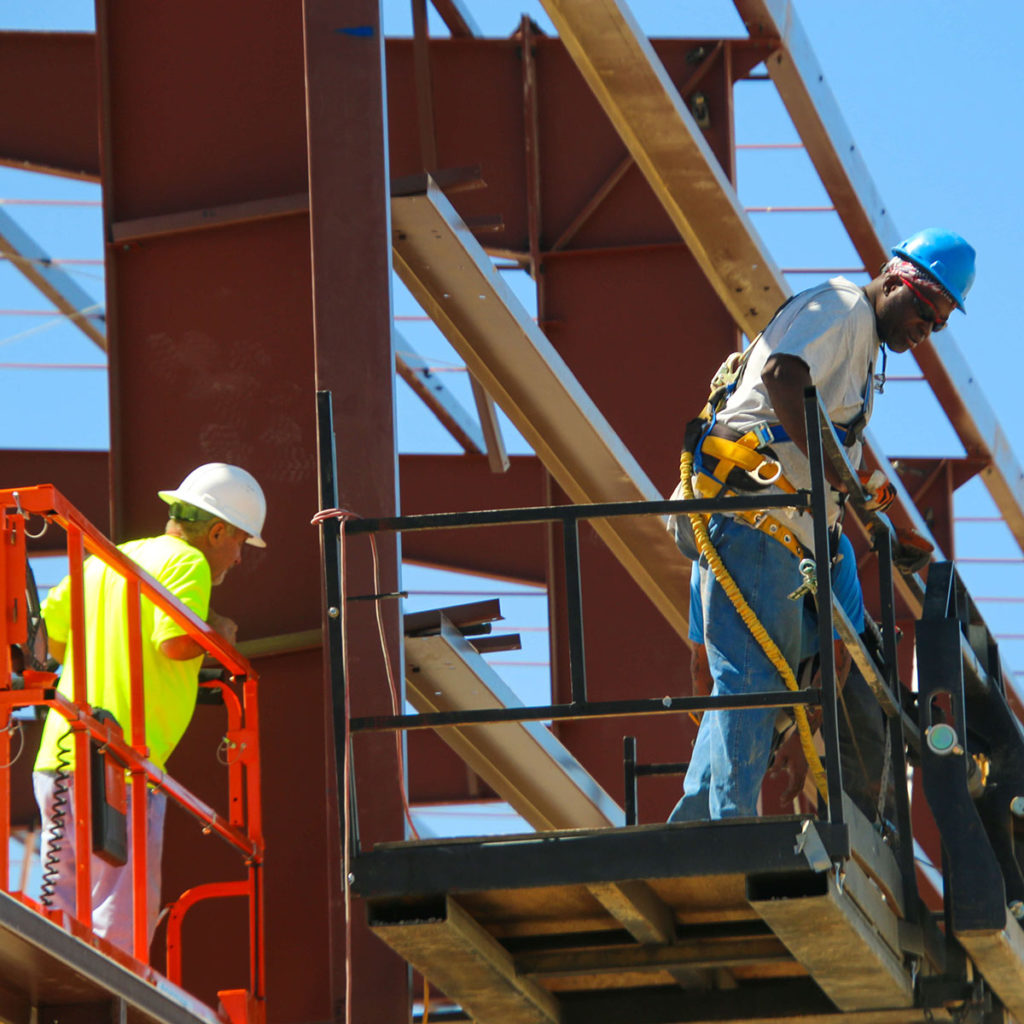 Construction workers on trusses and scissor lifts